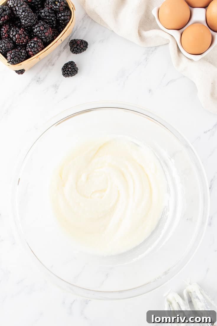 Butter, oil, and sugar being beaten together in a large mixing bowl with an electric mixer.