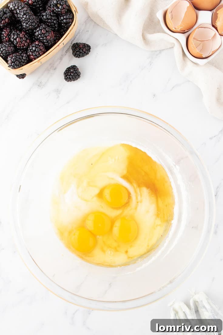 Adding an egg to the creamy butter and sugar mixture in a mixing bowl.