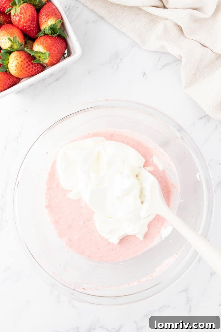 Mixing the whipped cream with the cream cheese mixture. 