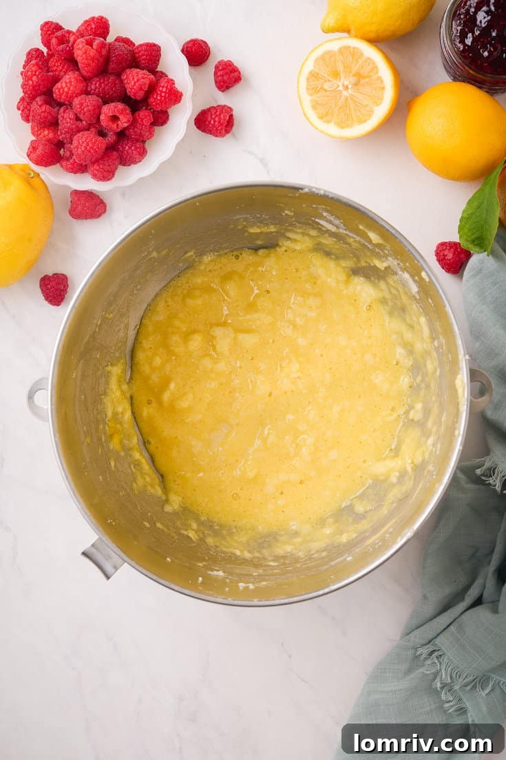 The beautifully smooth and creamy lemon cake batter, enriched with eggs, lemon juice, and extracts, being prepared in an electric mixer.