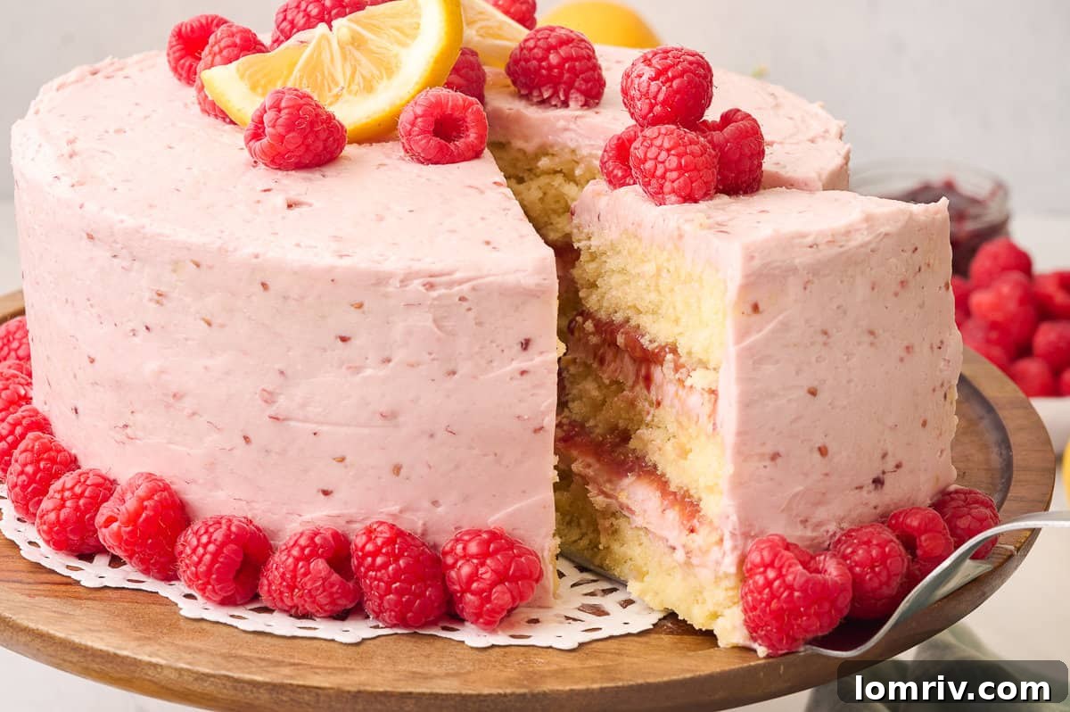 A beautifully composed shot of the Lemon Raspberry Cake on a cake stand, with a slice being removed, inviting viewers to indulge in its delicious layers.