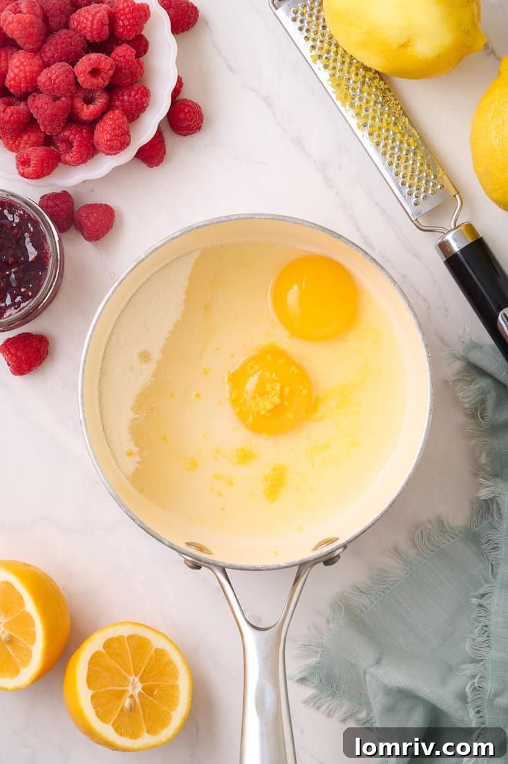 Whisking together egg yolks, lemon zest, lemon juice, and granulated sugar in a saucepan, creating a smooth, pale yellow mixture for the lemon curd.
