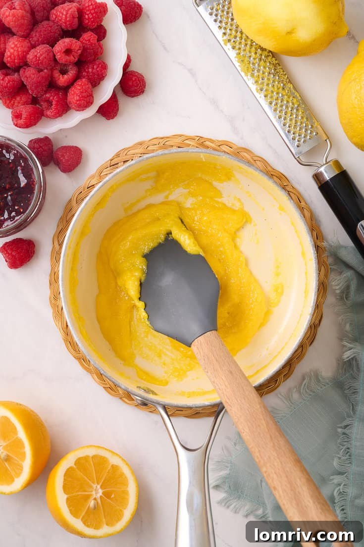 Cooking the lemon curd mixture over medium-high heat, continuously stirring with a spatula until it noticeably thickens and coats the back of the utensil.
