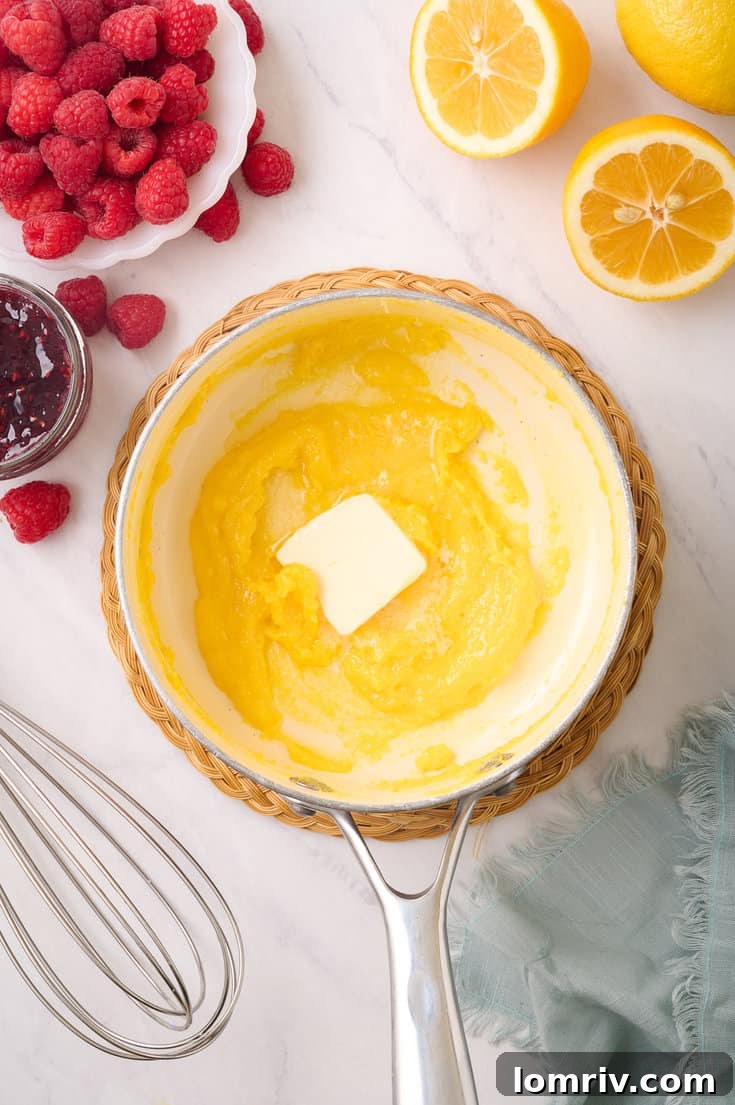 Adding cold, cubed butter to the warm lemon curd off the heat, and whisking continuously until the butter is fully melted and integrated, resulting in a smooth and shiny curd.