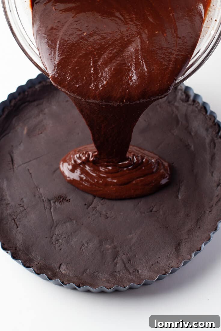 Pouring the smooth chocolate ganache into the chilled Oreo cookie tart shell