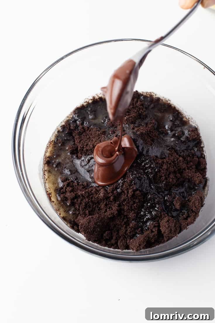 Melted butter being poured into crushed Oreo cookies for the tart crust
