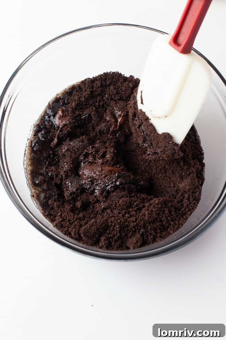 Mixing melted butter and Oreo crumbs to form the tart crust