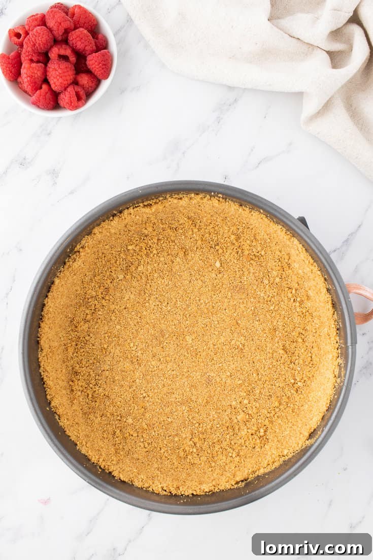 Firmly pressing the graham cracker crust mixture into a springform pan