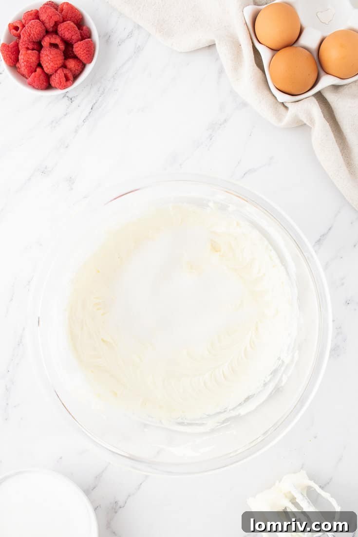 Beating softened cream cheese until smooth and creamy for cheesecake