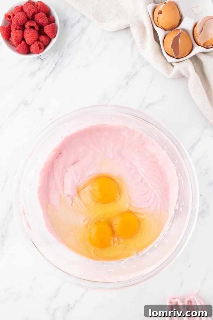 Adding eggs one by one to the cheesecake batter for smooth incorporation