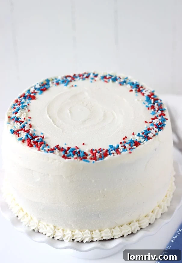 Vibrant red, white, and blue layered flag cake decorated with fresh berries and vanilla buttercream