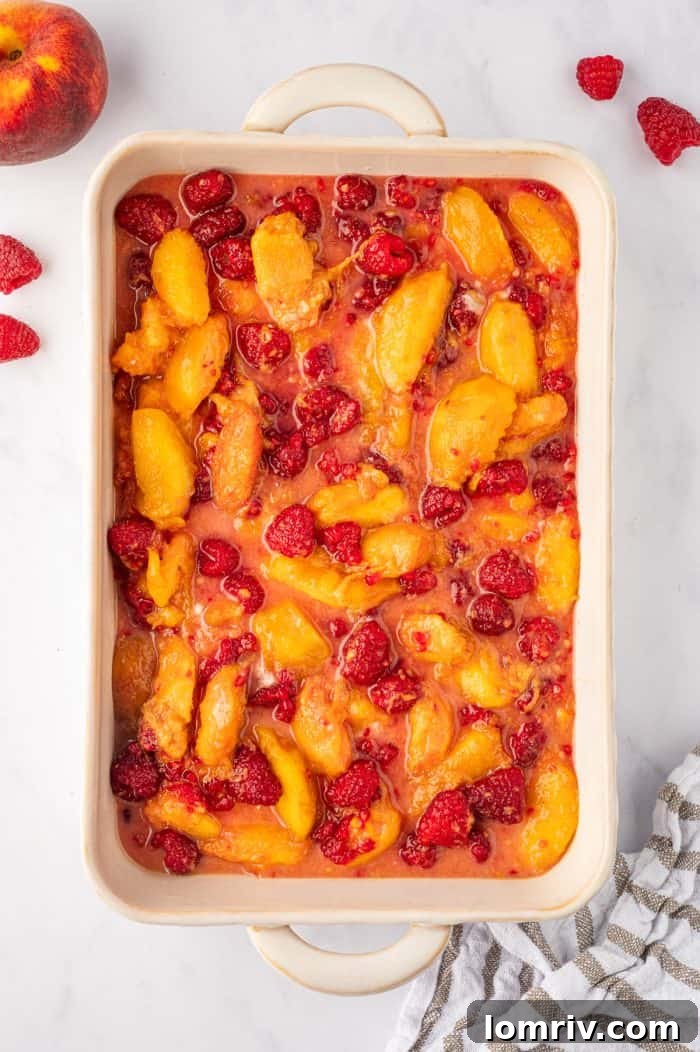 Peach raspberry filling neatly spooned into a baking dish, with emphasis on leaving behind any gathered excess juices.