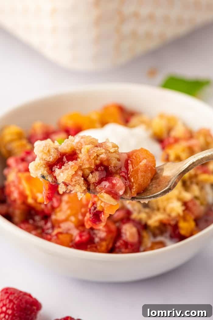 Close-up of the buttery, golden oat crumble topping on a peach raspberry dessert, highlighting its irresistible texture.