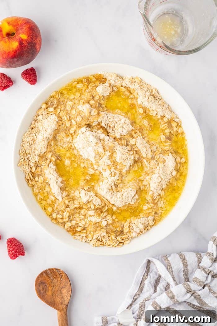Melted butter being drizzled into the dry crumble topping ingredients, beginning the process of forming delicious clumps.