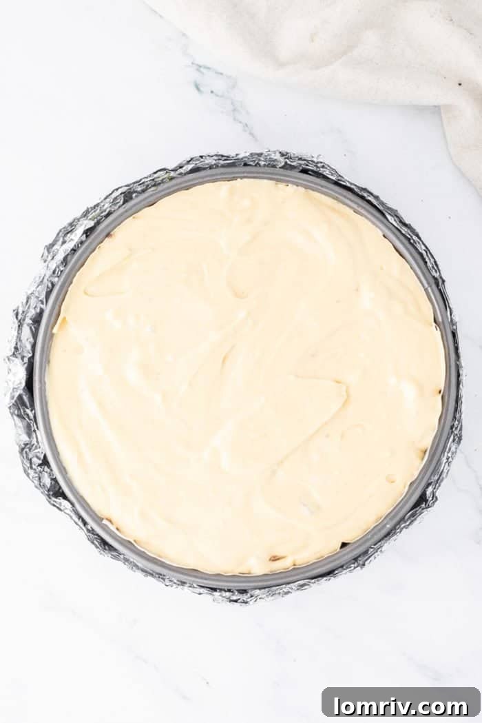 The Reese's Peanut Butter Cheesecake in its springform pan, smoothed and ready to be placed in the water bath for baking, promising a perfect texture.