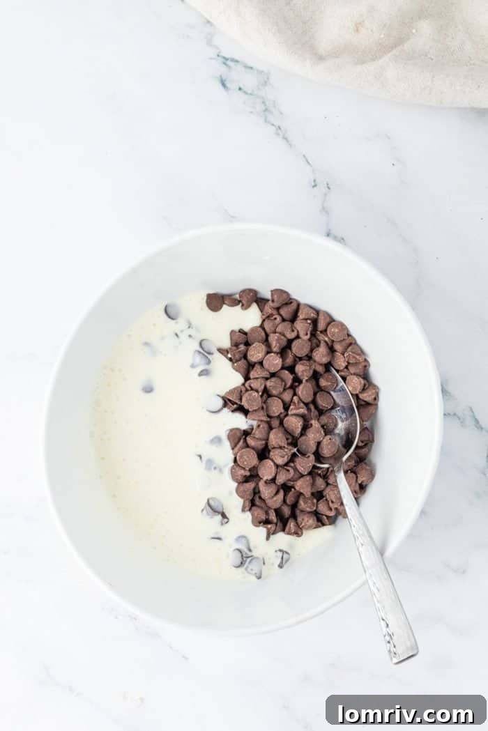 Semi-sweet chocolate chips and heavy cream combined in a small heat-safe bowl, ready to be microwaved to create the luscious chocolate ganache.