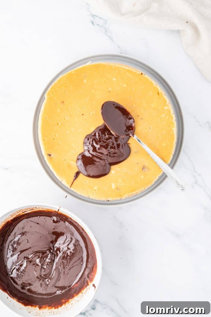 The smooth, rich chocolate ganache being carefully poured and spread over the perfectly chilled Reese's Peanut Butter Cheesecake, creating a luxurious top layer.