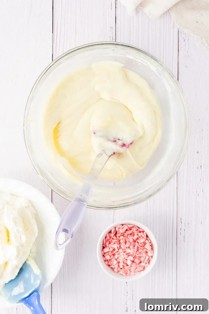 The creamy, smooth blend of cream cheese and melted white chocolate, perfectly combined in a glass bowl, showcasing a harmonious and inviting texture.