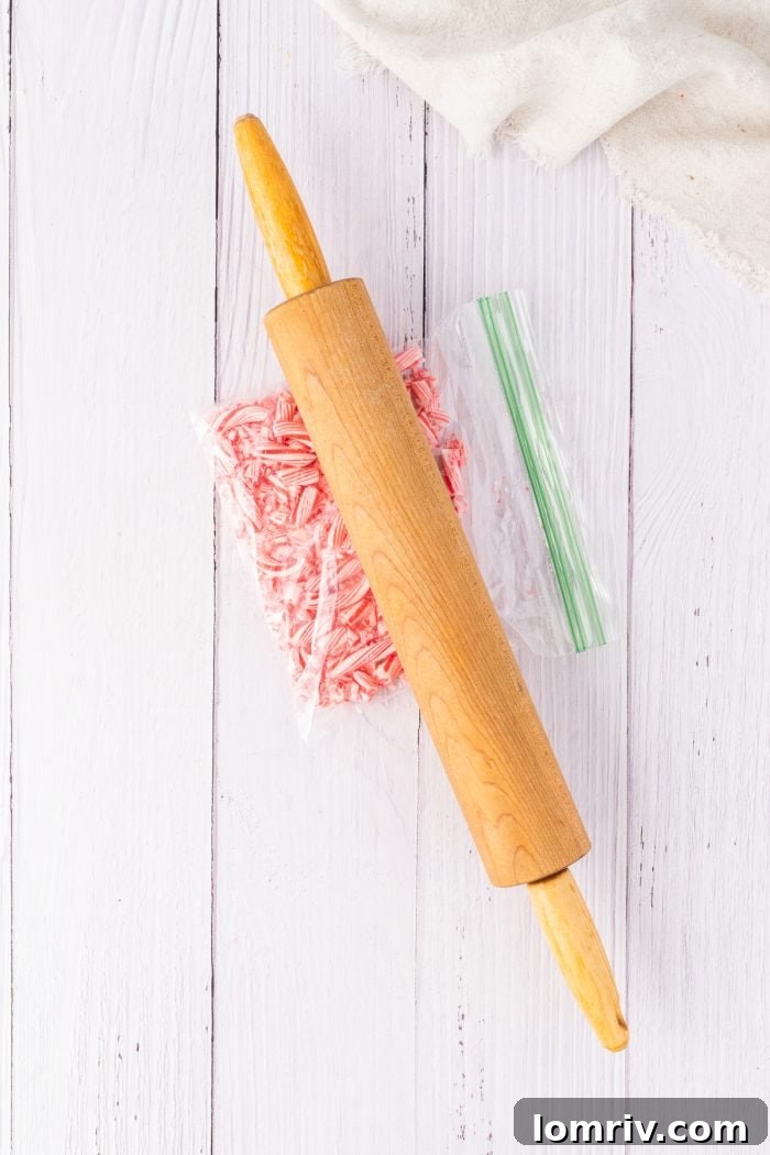 Crushing vibrant red and white candy canes with a sturdy rolling pin on a wooden surface, creating perfect peppermint pieces for the dessert.
