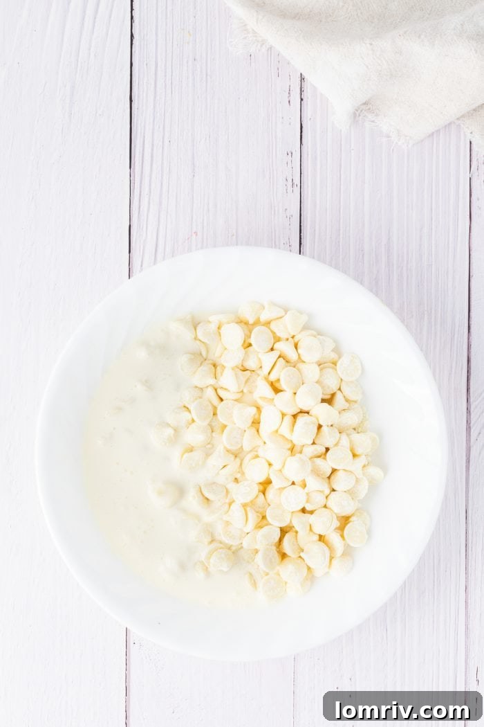 White chocolate chips and heavy cream, beautifully combined in a clean white bowl, ready to be melted into a luscious ganache.