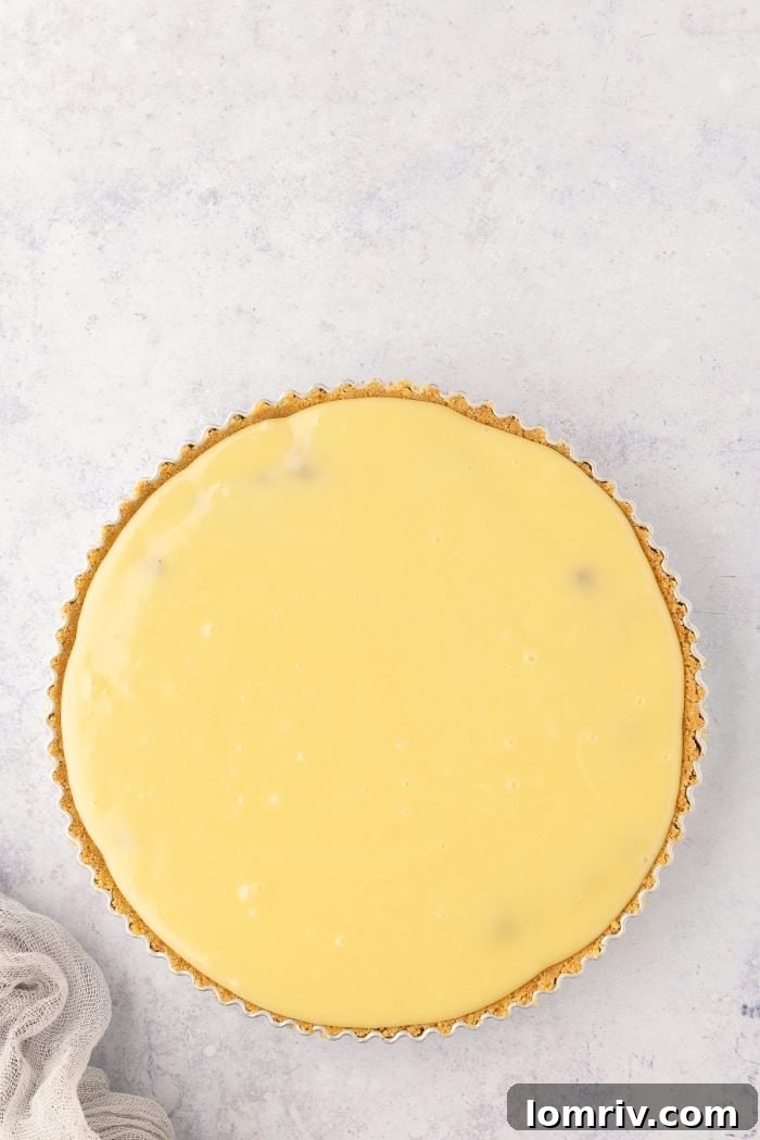 Smooth white chocolate ganache poured evenly over the cranberry layer in the tart.