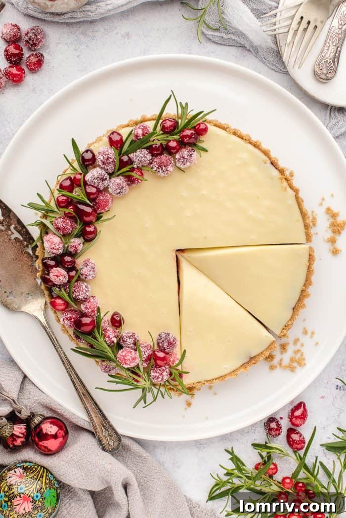 An overhead shot of a white chocolate cranberry tart on a white plate, with several slices already cut.