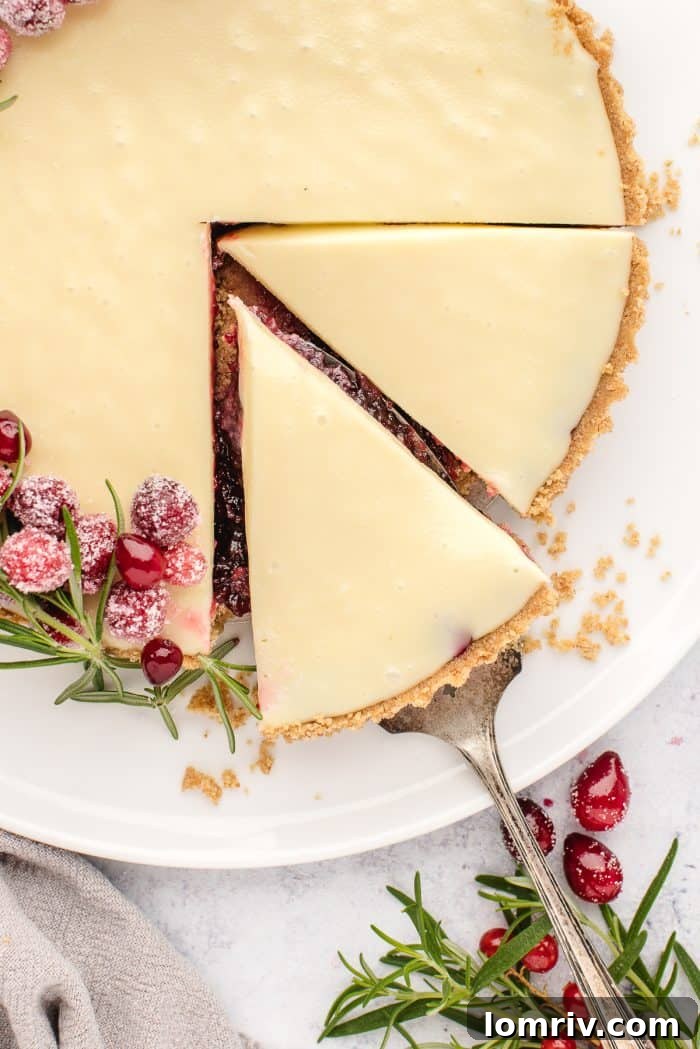 An overhead view of the elegant white chocolate cranberry tart, artfully decorated with sprigs of rosemary and fresh cranberries.