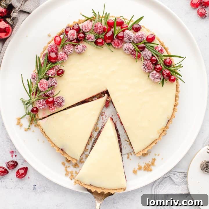 An overhead image of a white chocolate cranberry tart on a white plate with slices made into it.