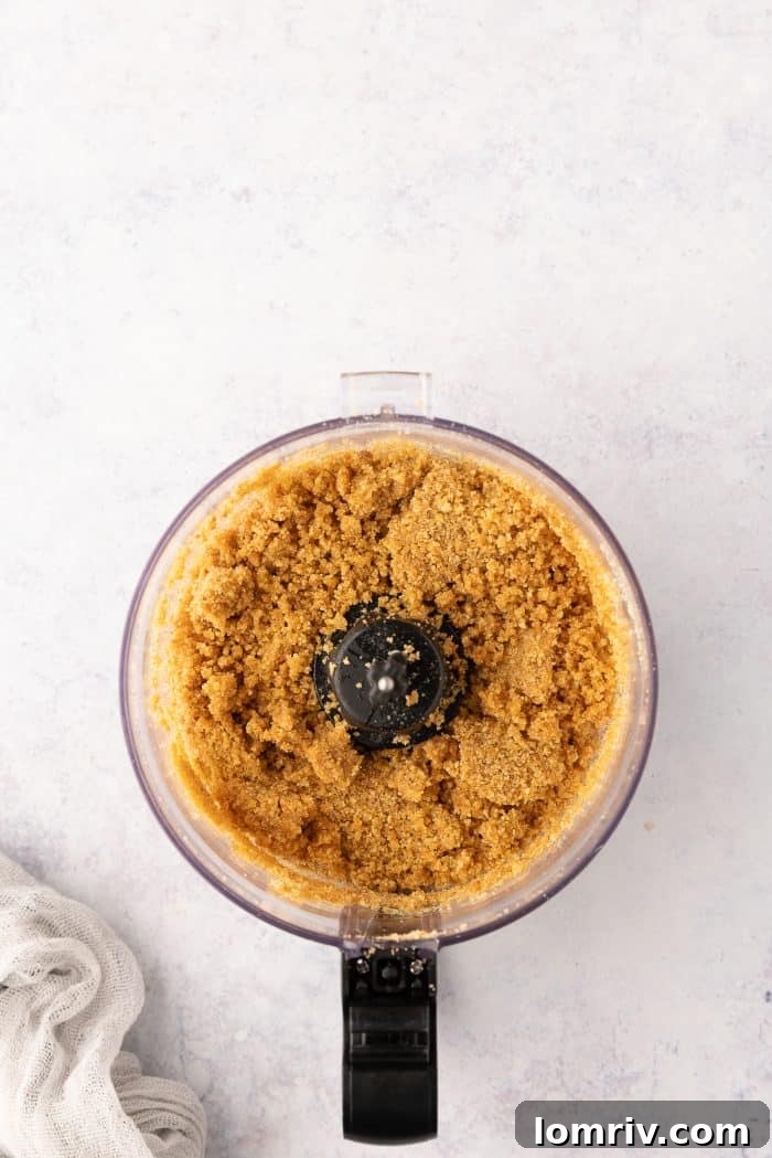 Graham cracker crumbs thoroughly mixed with melted butter in a food processor, forming the tart crust mixture.