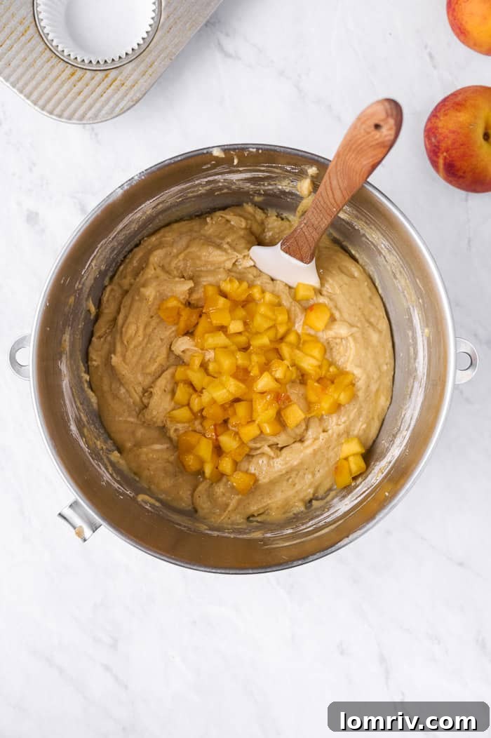 Folding in fresh diced peaches into the cupcake batter by hand