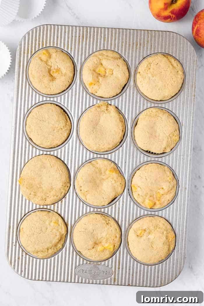Freshly baked brown butter peach cupcakes cooling in the muffin tin