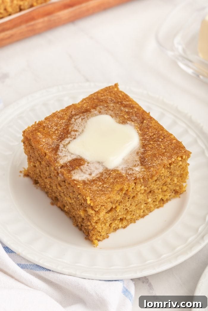 A plate with a slice of pumpkin cornbread with melted butter.