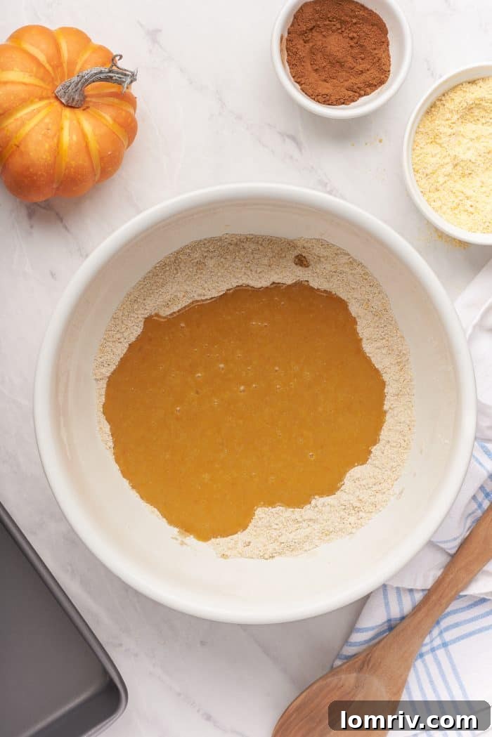 A white bowl with the liquid ingredients mixed with the dry ingredients.