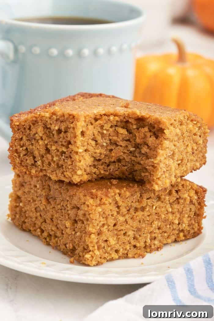 Two slices of pumpkin cornbread on a white plate with a bite taken out of it.