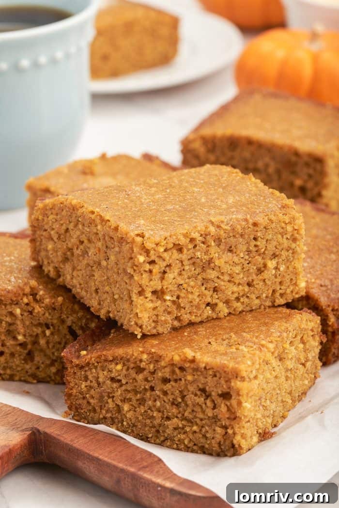 A stack of pumpkin cornbread on a wooden cutting board.