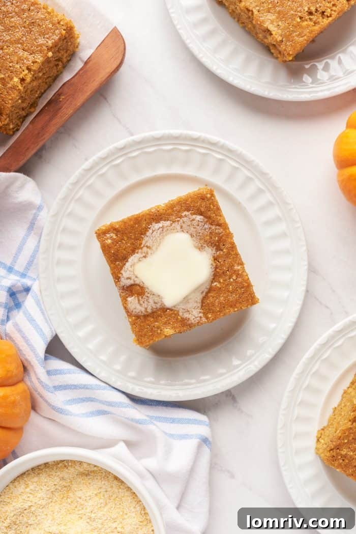 An overhead image of a slice of pumpkin cornbread with melted butter on a white plate.
