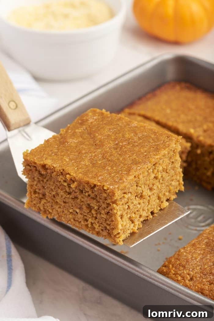 A slice of pumpkin cornbread being lifted from the baking pan.