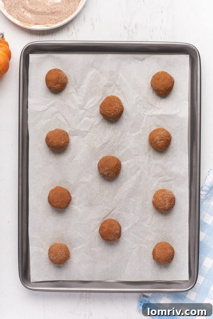 A baking sheet with parchment paper with balls of raw cookie dough.