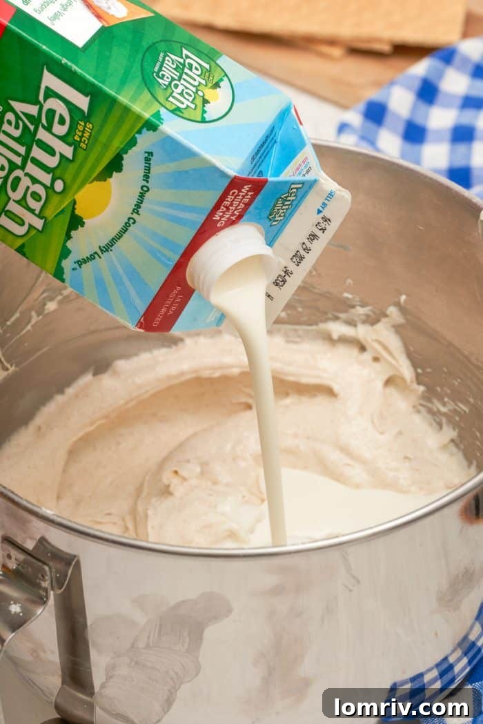 Lehigh Valley heavy cream being poured into a bowl containing the cream cheese mixture, ready to be incorporated.