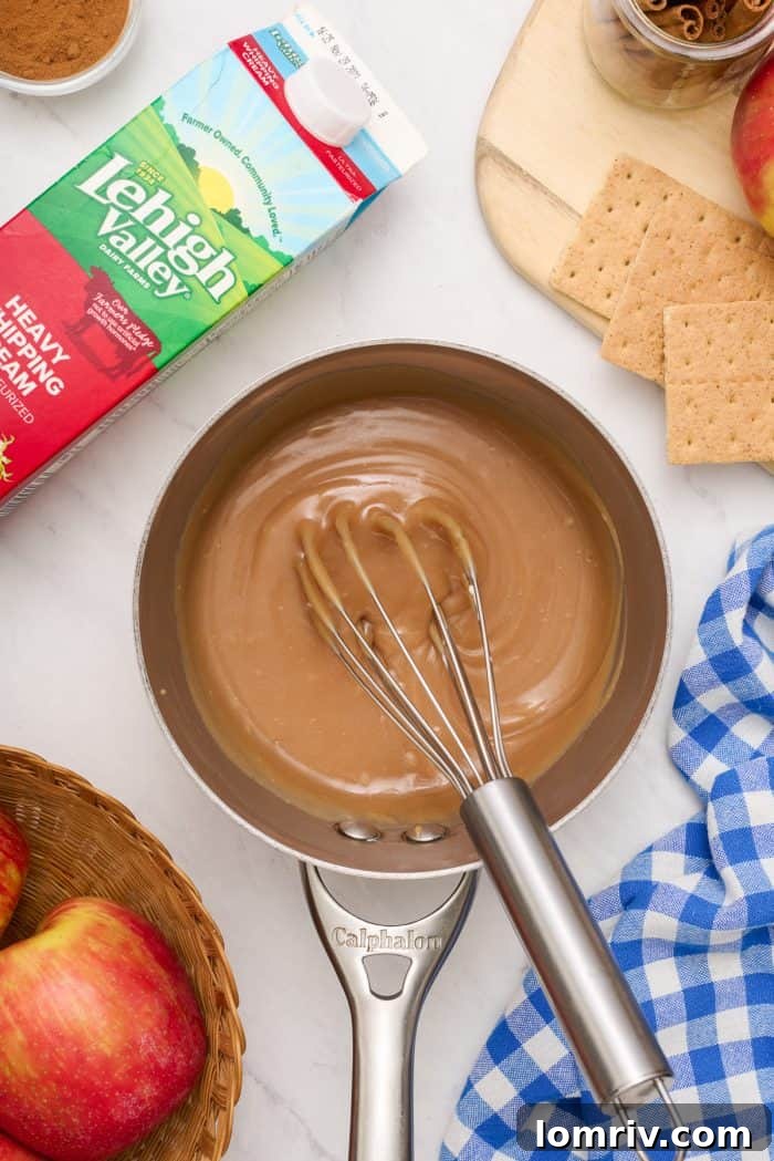 A saucepan containing perfectly smooth, golden caramel, with a whisk resting inside after mixing.