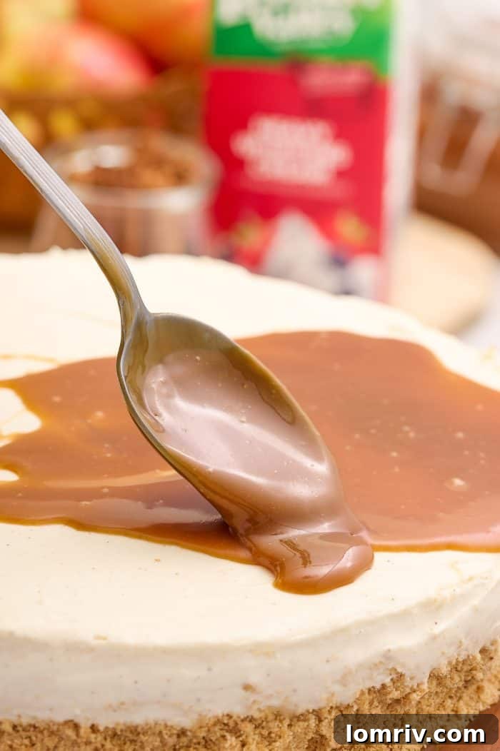 Rich caramel sauce being spooned generously over the set no bake cheesecake, creating an inviting visual.
