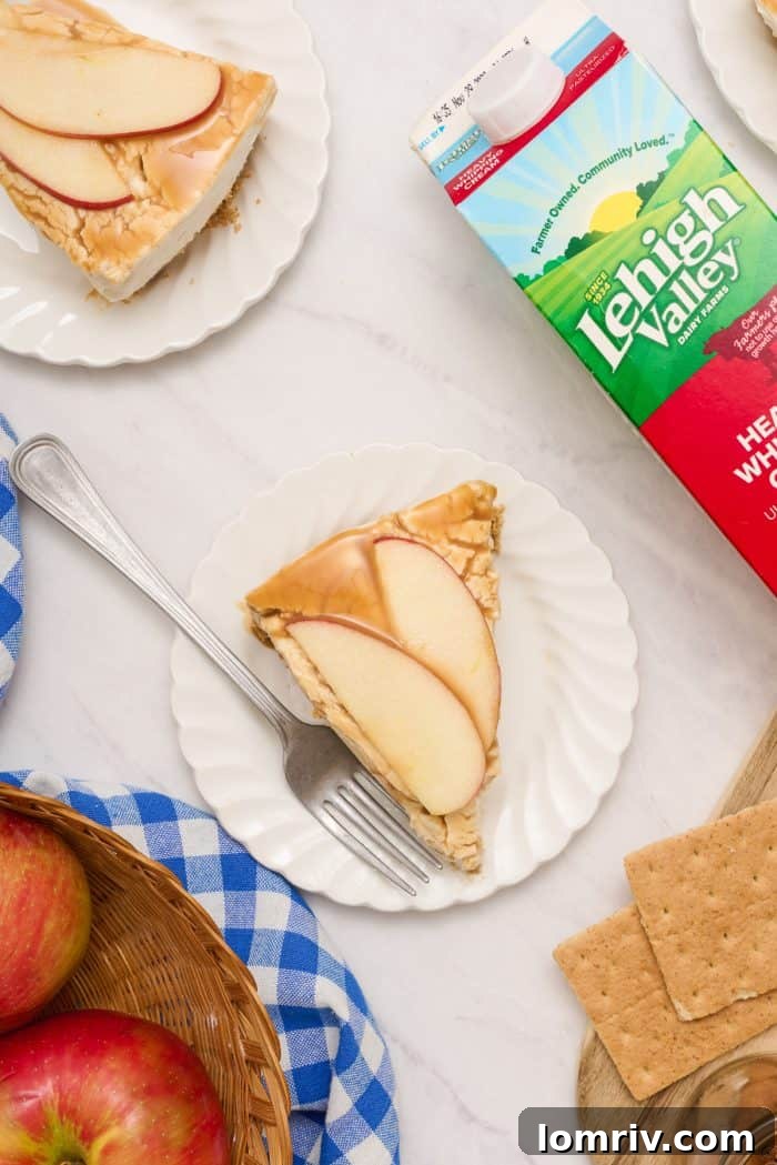 Two pristine white plates, each holding a perfect slice of apple caramel cheesecake, ready for serving.