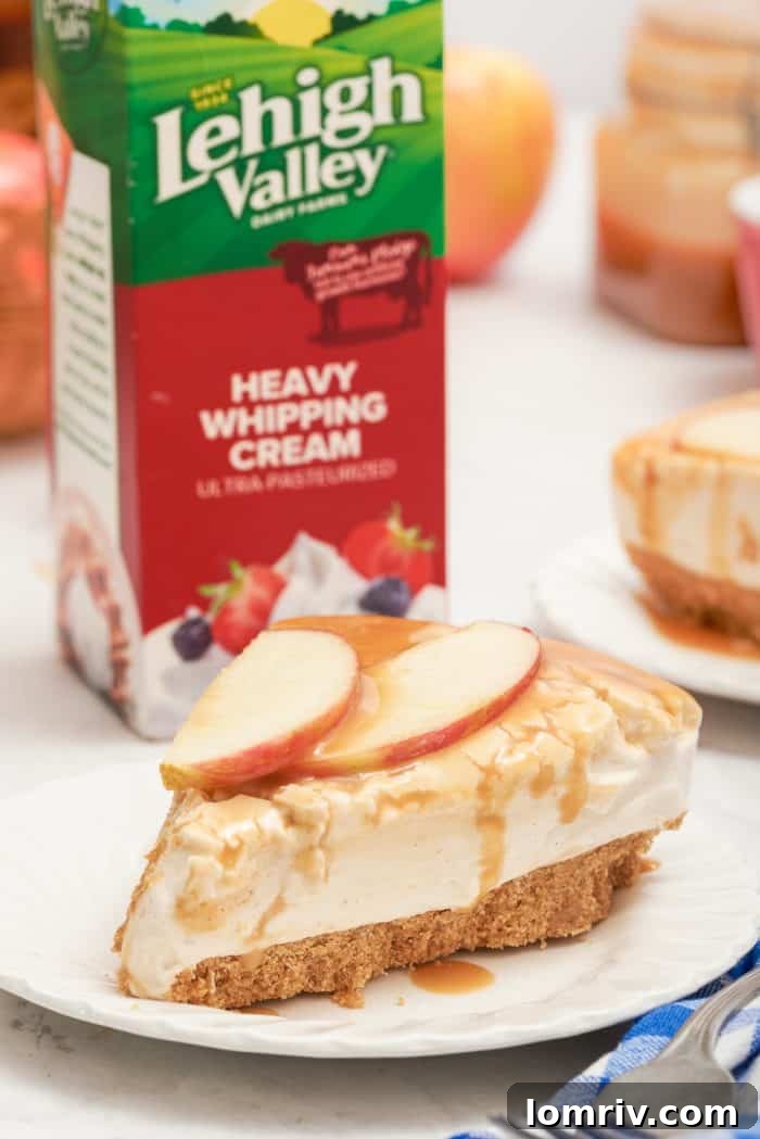A close-up view of a slice of apple cheesecake, with a carton of Lehigh Valley heavy whipping cream in the softly blurred background.