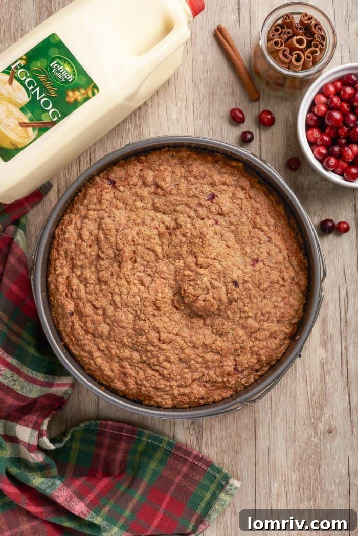 A beautifully baked golden-brown coffee cake, still warm in its round cake pan, having just emerged from the oven.