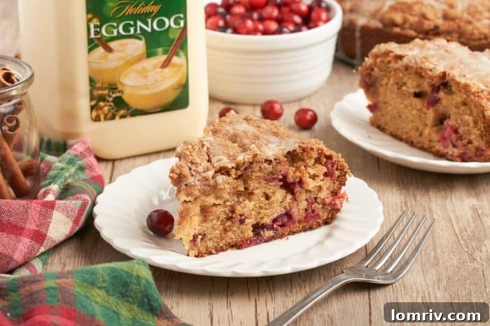 A charming close-up of a single slice of cranberry eggnog coffee cake on a white plate, highlighting its inviting layers and perfect presentation.