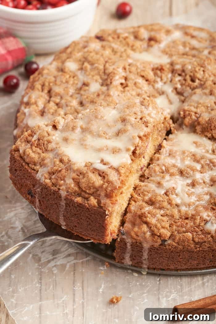 A delectable slice of cranberry eggnog coffee cake being carefully lifted from the pan with a cake server, revealing its tender crumb and layers of flavor.