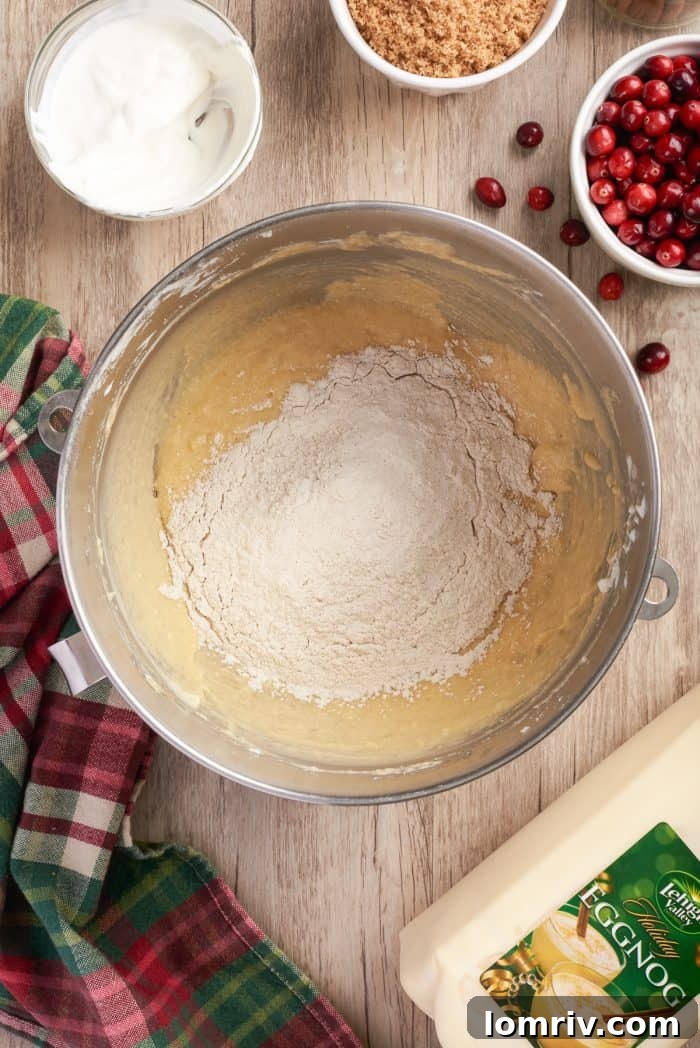 The creamed butter and sugar mixture in a bowl, with the first batch of dry ingredients freshly added, ready for mixing.