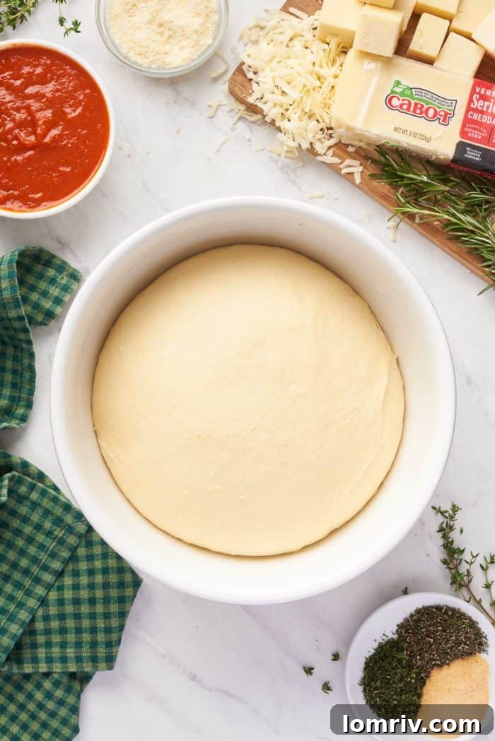 The dough, beautifully risen and doubled in size, fills a white bowl, indicating it's perfectly proofed and ready for shaping.