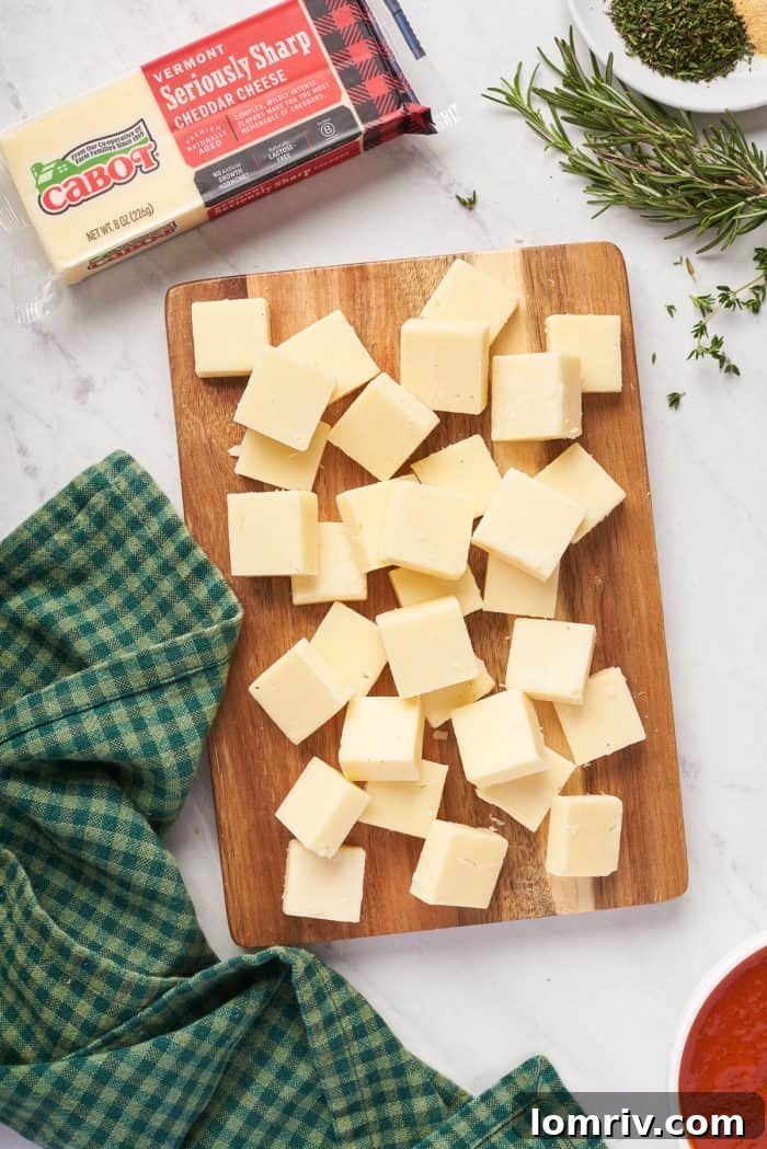 Perfectly uniform cheddar cheese cubes, neatly arranged, awaiting their role as the gooey center of each bread ball.