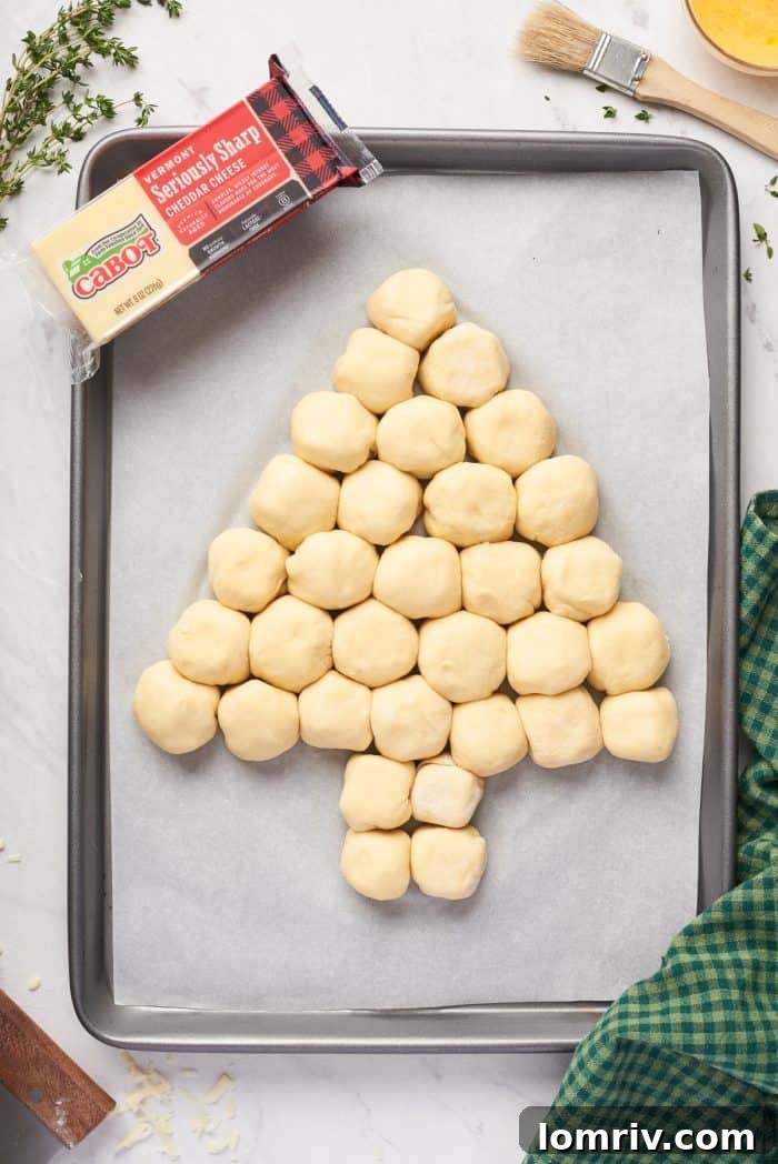 Dough balls perfectly arranged on a baking sheet to form a Christmas tree shape, ready for their final rise.